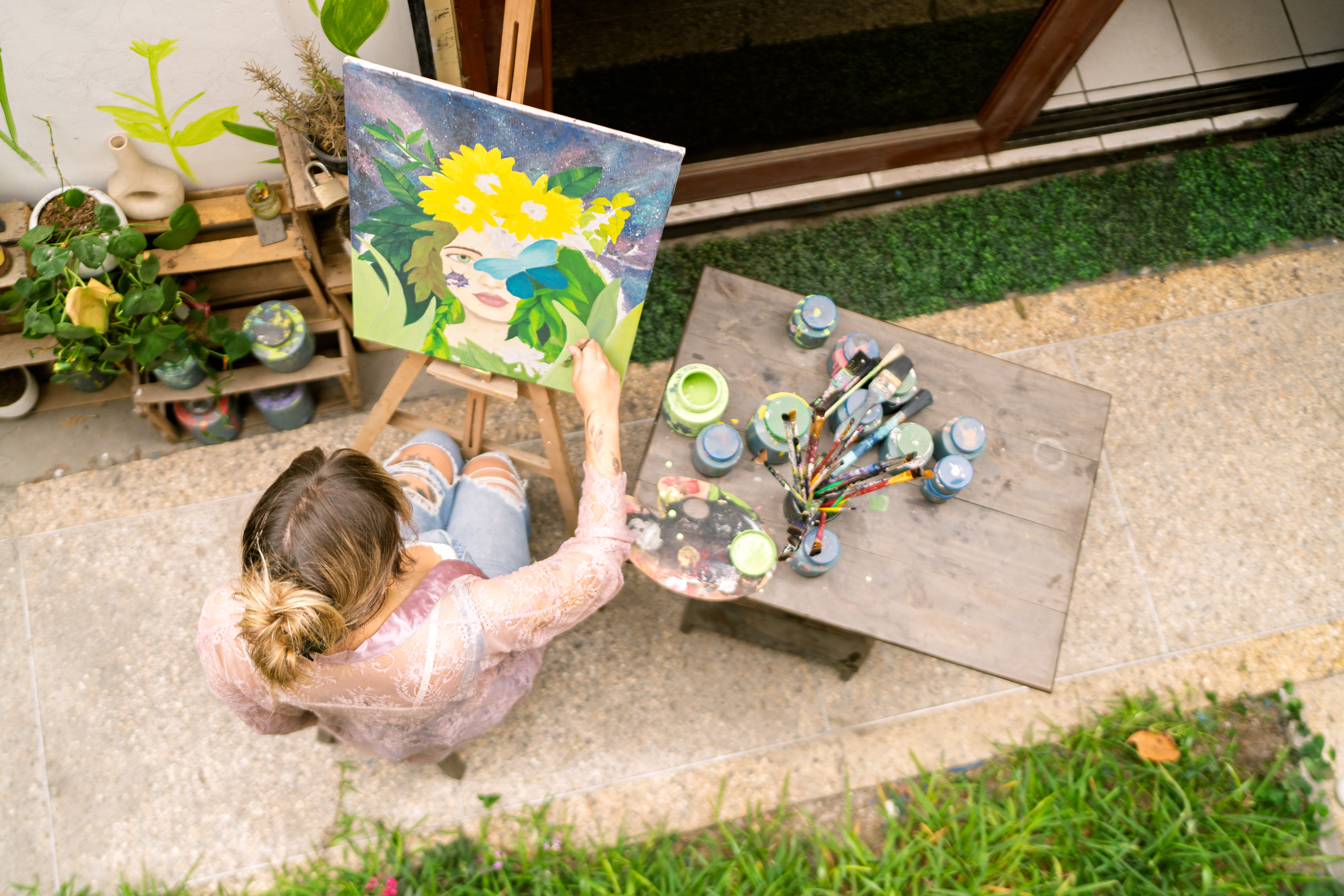 Creative woman artist painting a colorful artwork on canvas outdoors, holding a palette and brush, expressing her talent and passion